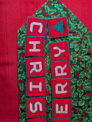 "Merry Christmas" Plastic Canvas Banner with green, red, and white stitched yarn