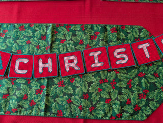 "Merry Christmas" Plastic Canvas Banner with green, red, and white stitched yarn