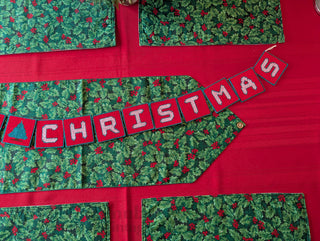 "Merry Christmas" Plastic Canvas Banner with green, red, and white stitched yarn