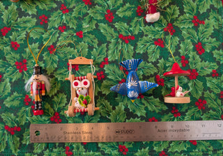 Set of Christmas-themed ornaments on a green leafy background with a ruler for scale.