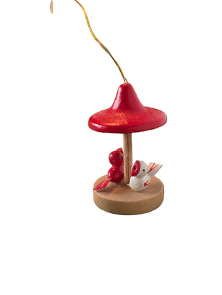 Decorative Christmas ornament with red top and white rabbit figure on a green holly-patterned tablecloth.