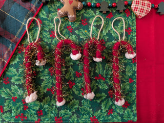 Decorative Christmas ornaments shaped like candy canes on a green fabric background.