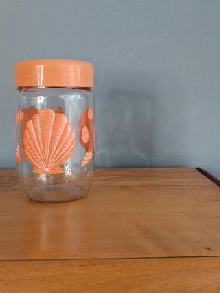 Seashells on a glass storage jar with orange plastic lid - Artful Accumulator Boutique Vintage