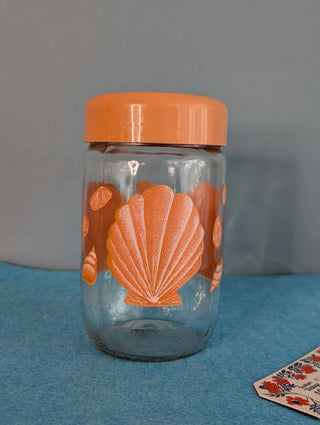 Seashells on a glass storage jar with orange plastic lid - Artful Accumulator Boutique Vintage