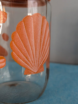 Seashells on a glass storage jar with orange plastic lid - Artful Accumulator Boutique Vintage