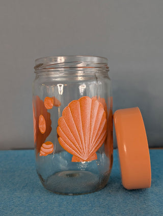 Seashells on a glass storage jar with orange plastic lid - Artful Accumulator Boutique Vintage