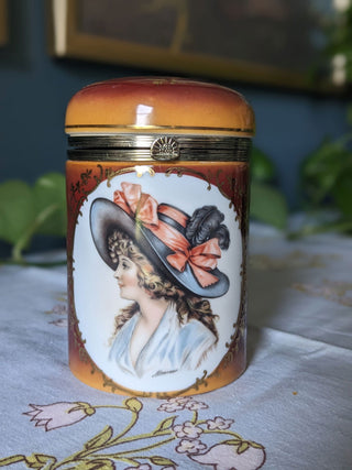 Trinket bureau jar with 24kt gold lustre and a decal of a beautiful woman in a feathered hat with curly hair and bows. Brass clasp & hinge. -  - #tag1# - #tag2# - #tag3# - #tag4# - the Artful Accumulator's Vintage Boutique
