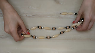 Necklace with long ivory beads, black beads, and mottled brown beads