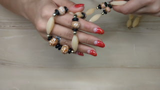 Necklace with long ivory beads, black beads, and mottled brown beads